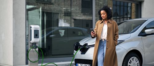 Frau vor E-Auto an der Ladesäule